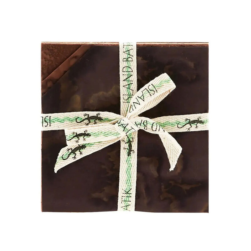 Layered stack of brown mottled fabrics with the upper left corners folded, tied in an “Island Batik” ribbon.