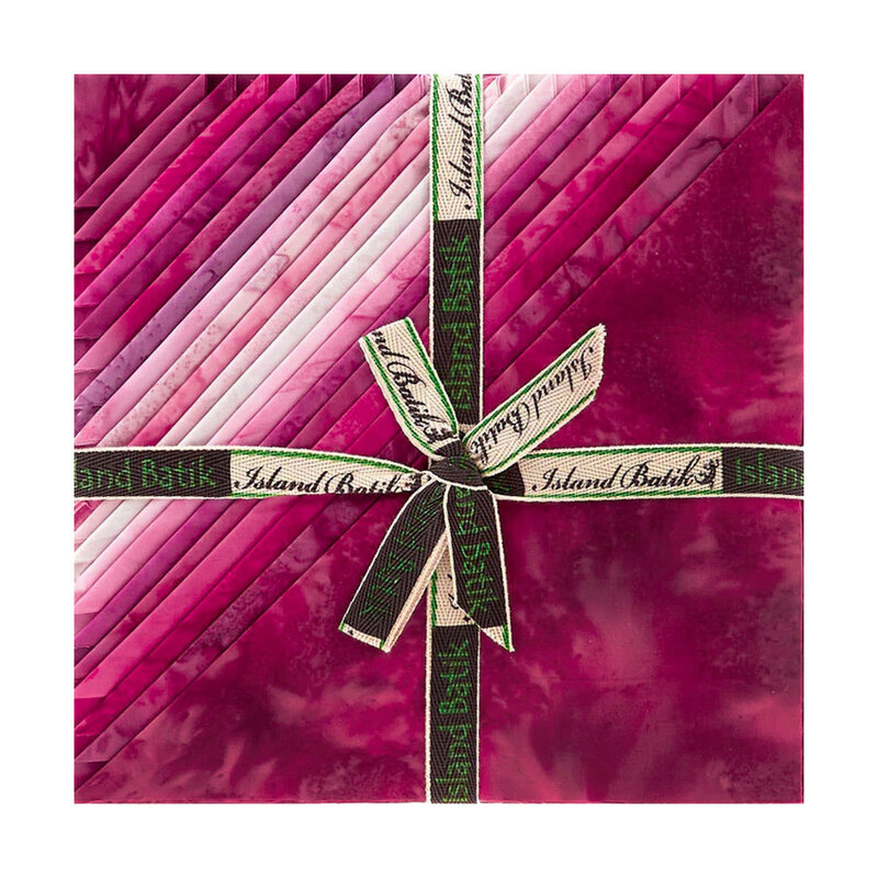 Layered stack of pink mottled fabrics with the left corners folded, tied in an “Island Batik” ribbon.