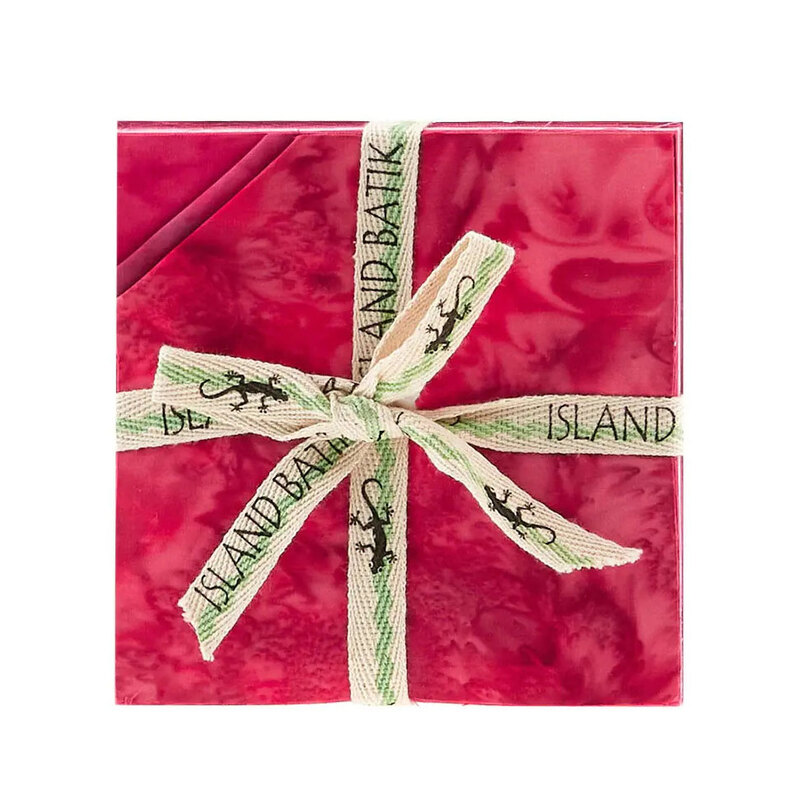 Layered stack of pink mottled fabrics with the upper left corners folded, tied in an “Island Batik” ribbon.