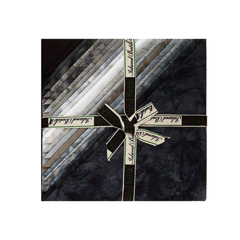 Layered stack of black, grey, and white mottled fabrics with the left corners folded, tied in an “island Batik” ribbon.