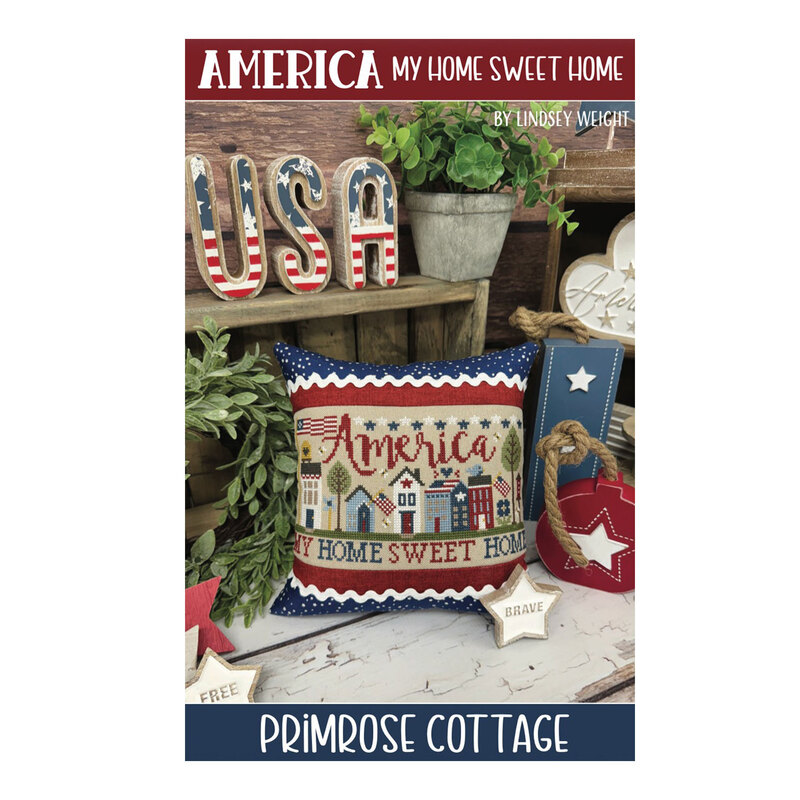 Front of the cross stitch pattern showing the finished design on a pillow with patriotic decor in the background.