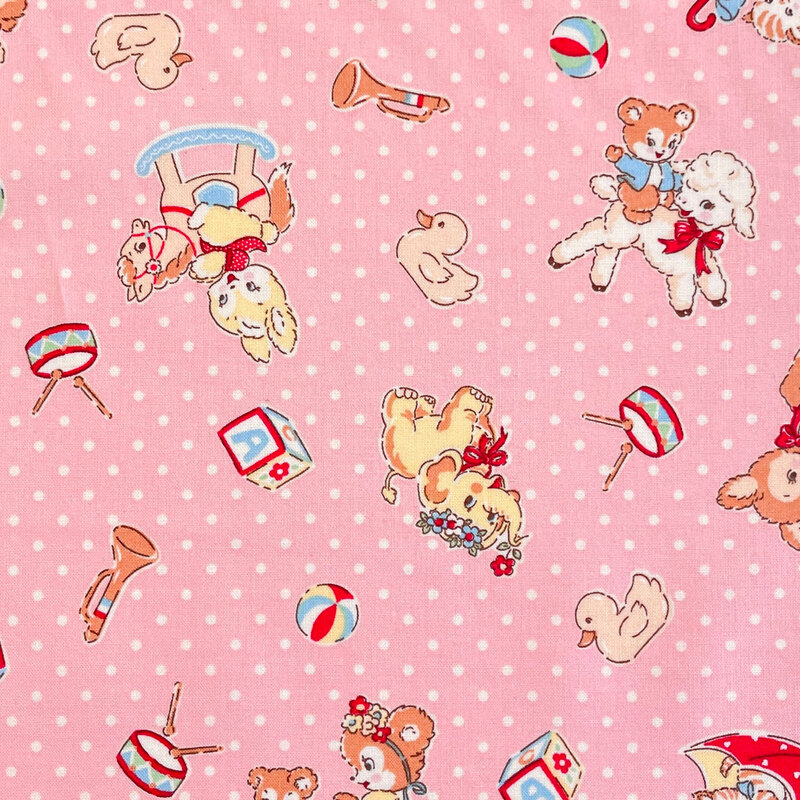 Pink fabric with a vintage-inspired design of cartoon animals and other childhood motifs scattered across a background of white dots.