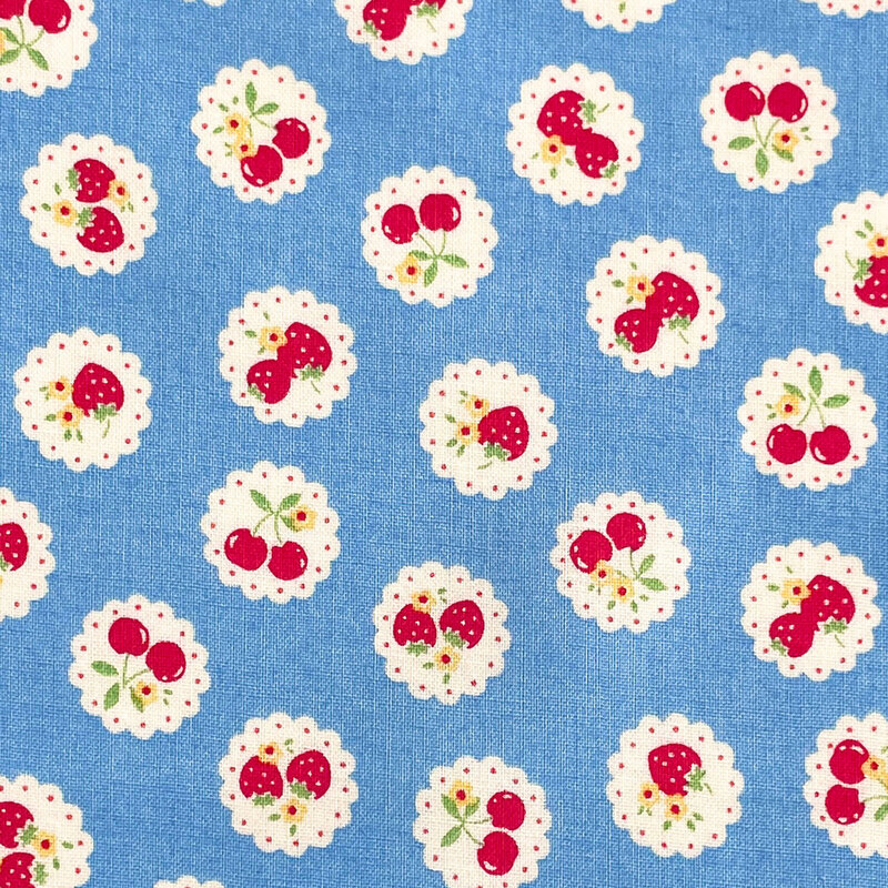 Blue fabric with a pattern of vintage-style medallions filled with assorted fruits like cherries and strawberries.