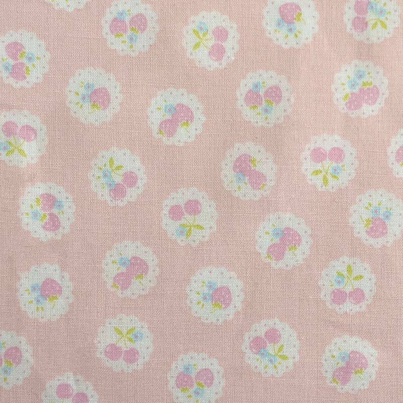 Light pink fabric with a pattern of vintage-style medallions filled with assorted fruits like cherries and strawberries.