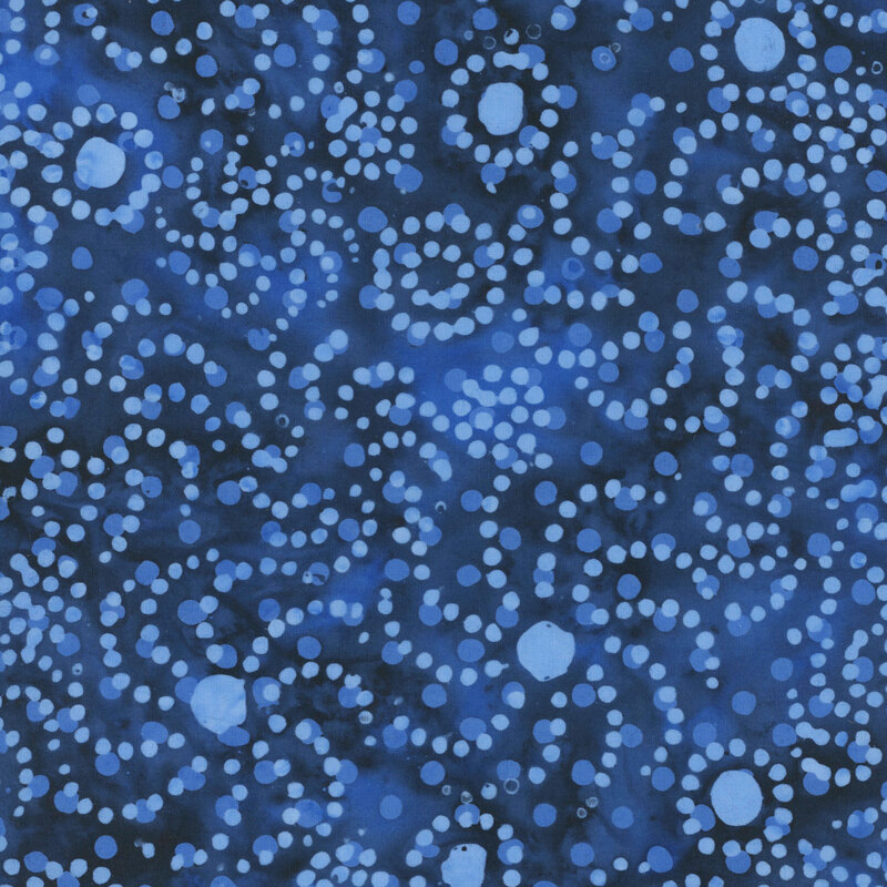 Mottled indigo and lapis blue fabric with a tonal overlay of polka dots as well as bright blue circles and dots in whirl designs