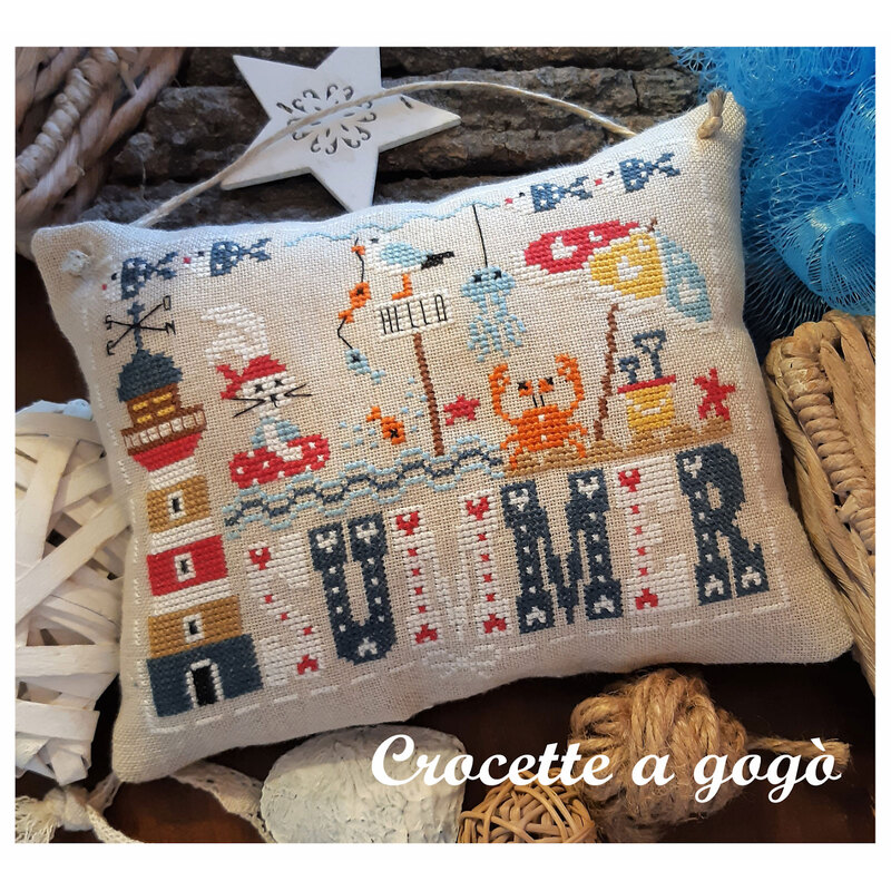 Embroidered pillow featuring a seaside theme with a lighthouse, crab, seashells, and the word SUMMER.