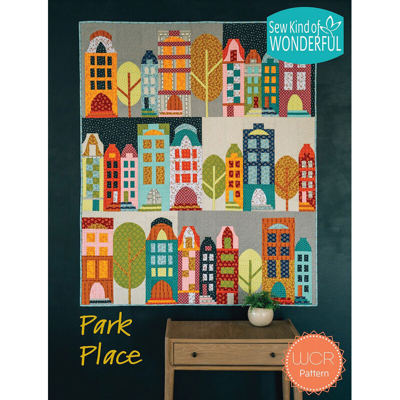 Colorful quilt design titled Park Place, featuring stylized houses and trees, displayed on a wall.