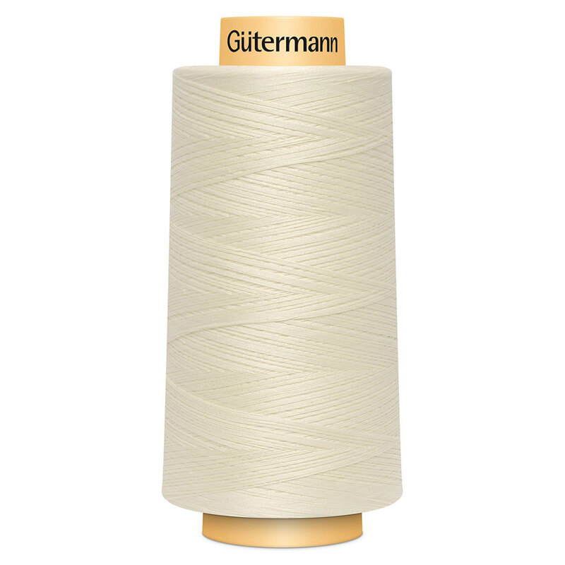 A spool of Gütermann Cotton Thread - Egg White thread on a white background