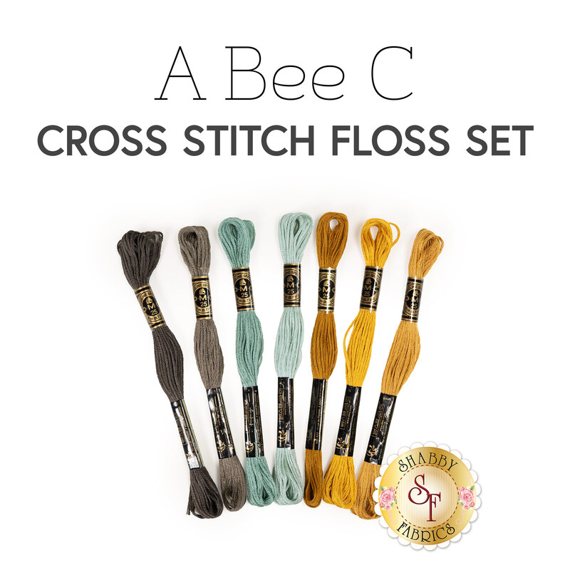 A set of seven cross stitch floss threads in brown, teal, yellow, and gold colors below a text graphic..