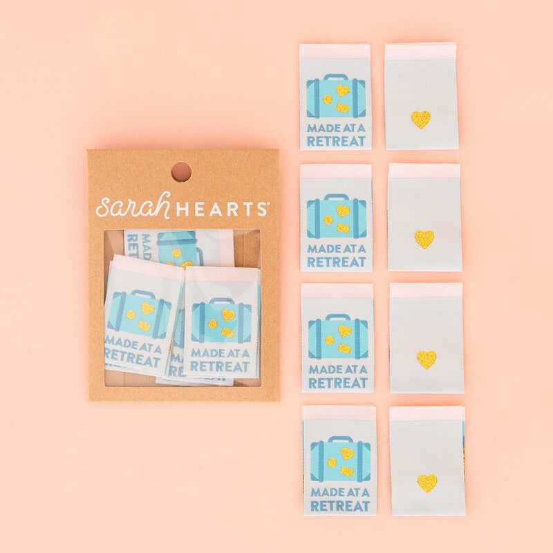 A package of Made at a Retreat Sew In Labels next to 8 individual labels on a pink background to show scale and detail.