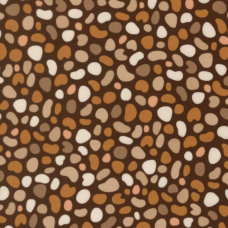 Dark brown fabric featuring pebble shaped motifs in hues of tan, taupe, mushroom, blush, and ivory.