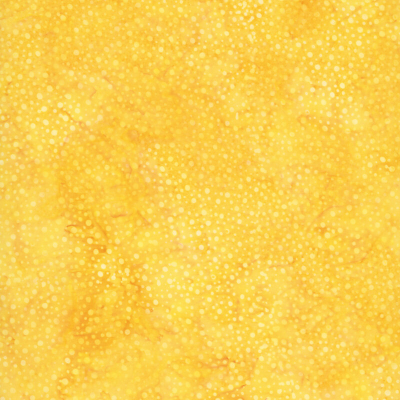 Swatch of yellow tonal batik with mottling and irregular dots.