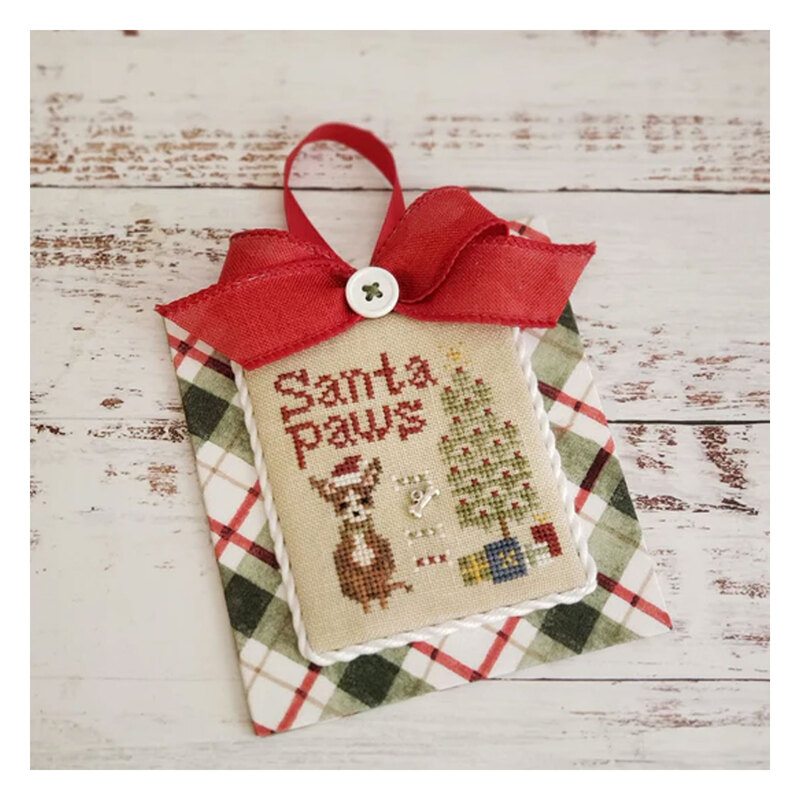The completed Santa Paws cross stitch project, staged on a distressed wooden table.