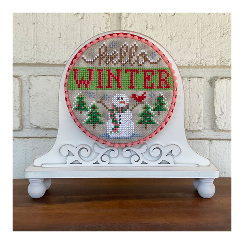 The completed Hello Winter cross stitch project, displayed on a coordinating cross stitch display stand.