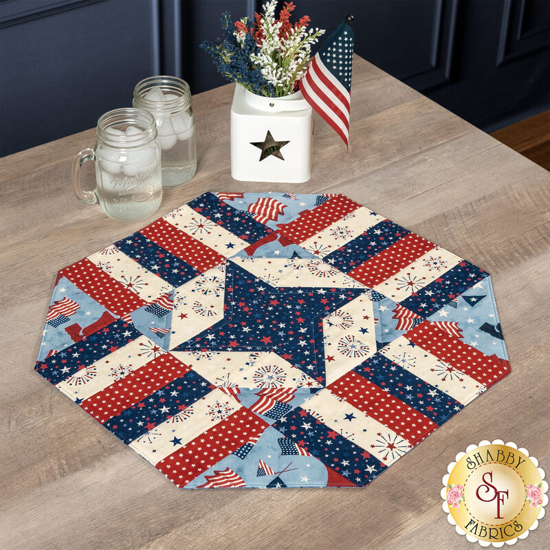 The completed Easy Patriotic Table Topper Kits finished in American themed fabrics from the Founding Glory collection by Wilmington Prints, set on a wooden table and surrounded by coordinating décor.
