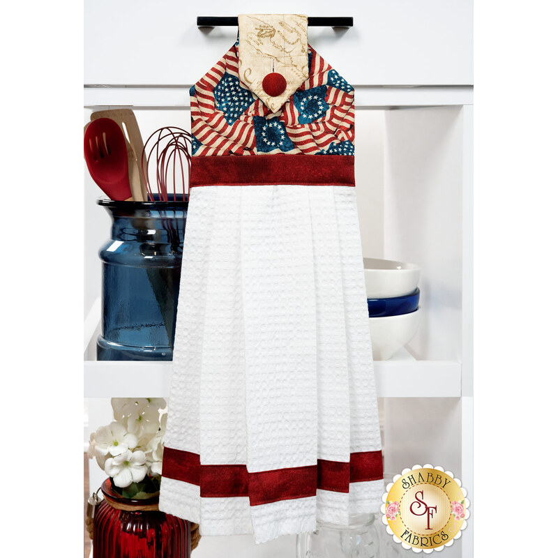 The completed Hanging Towel Kit colored in red, white, and blue fabrics from the American 250 - Stonehenge collection by Northcott Fabrics, hung on a drawer surrounded by coordinating patriotic décor. 