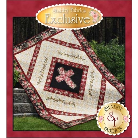 A quilt featuring a floral pattern with a prominent cross design in the center, set against a black background. The quilt is bordered with a rich reddish-brown fabric and displayed outdoors on stone steps with greenery in the background. The text Shabby Fabrics Exclusive is prominently featured at the top.