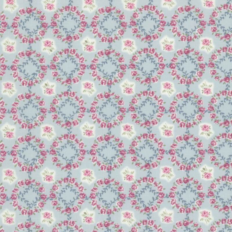 Ice blue fabric layered with a grid of mauve-pink rose wreaths and roses.
