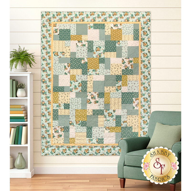 The completed Easy as ABC and 123 Quilt Kit colored in teal, cream, and ocher fabrics from the Renew collection by Riley Blake Designs, displayed on a cream shiplap wall and staged with coordinating décor.