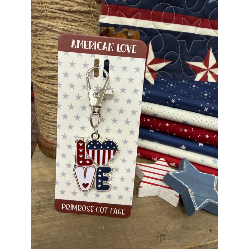 The American Love Charm with its paper packaging insert, staged with coordinating patriotic decor.