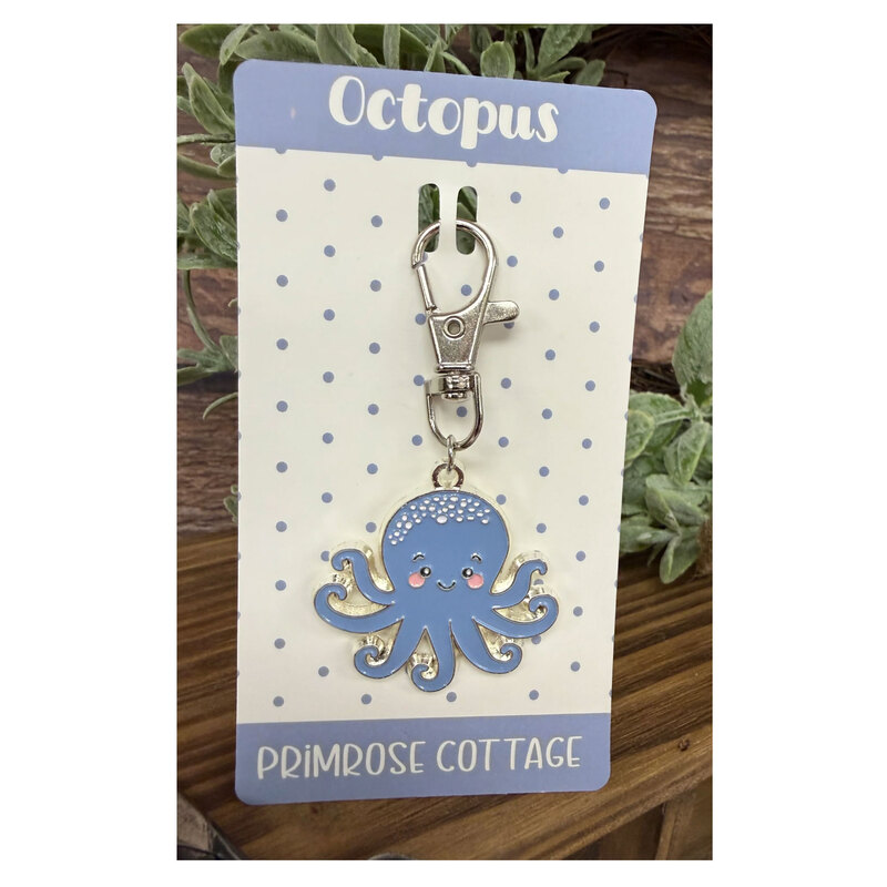 The Octopus Charm with its paper packaging insert, staged with coordinating decor.