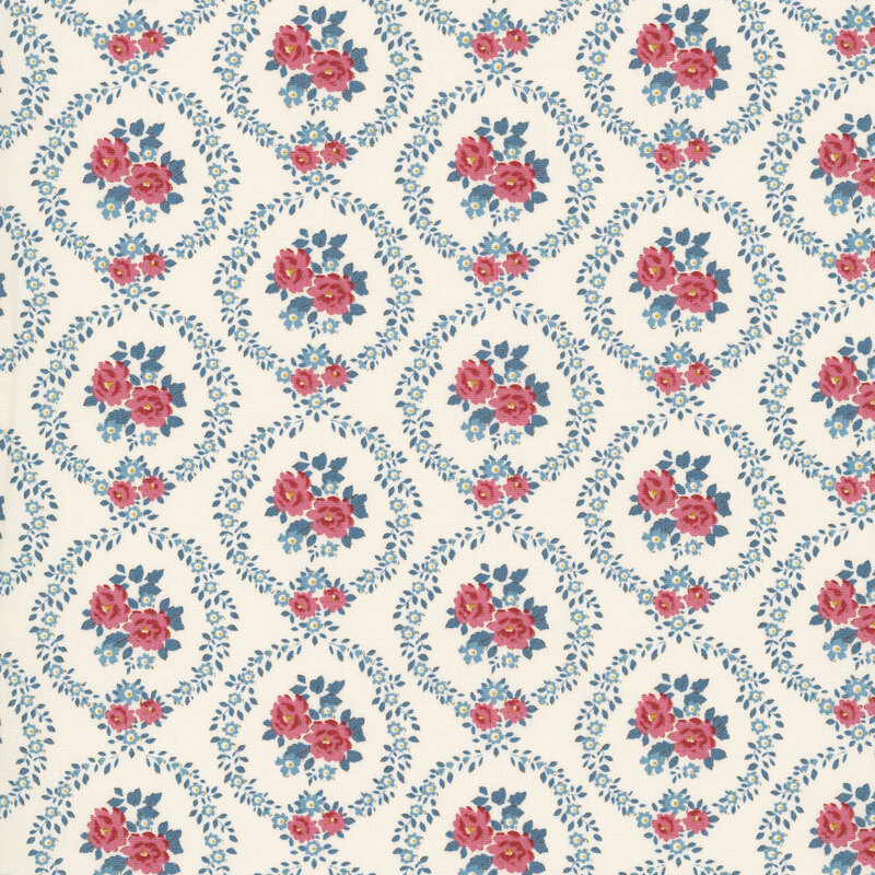 This white fabric features burgundy and blue floral wreaths framing centerpieces. 