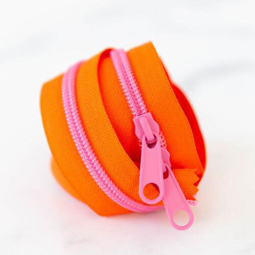 A twisted length of neon orange zipper tape with pink pull tabs against a light background.