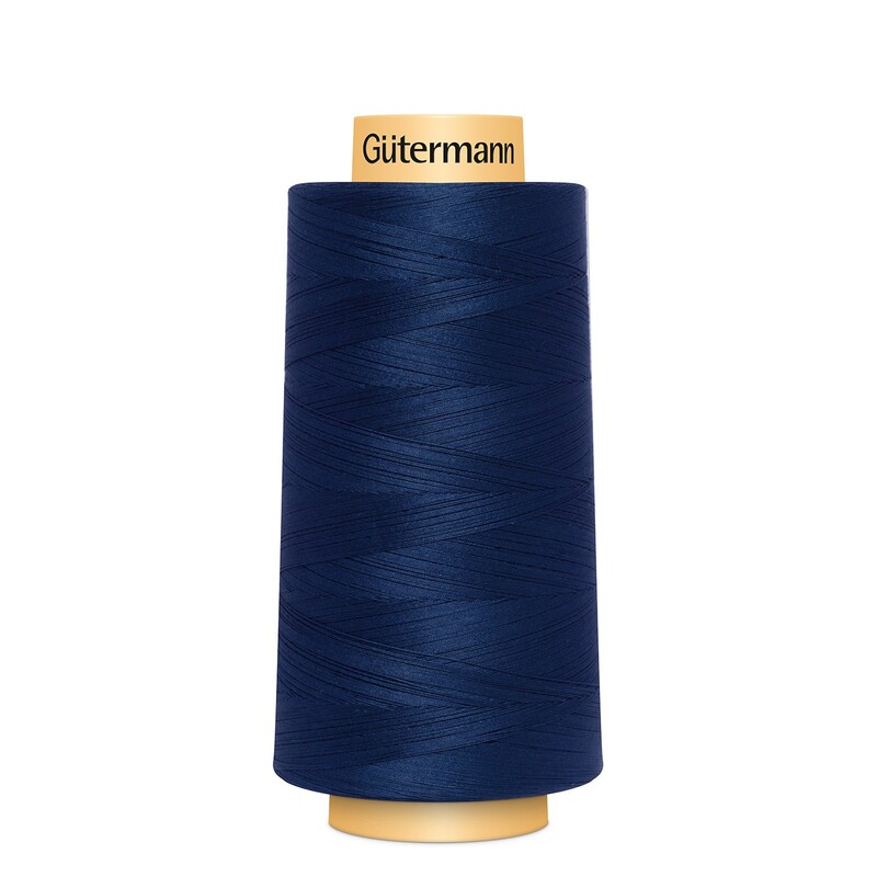 A spool of Gütermann Cotton Thread - Navy thread on a white background