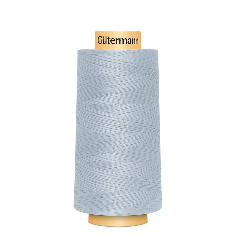 A spool of Gütermann Cotton Thread - Light Blue thread on a white background