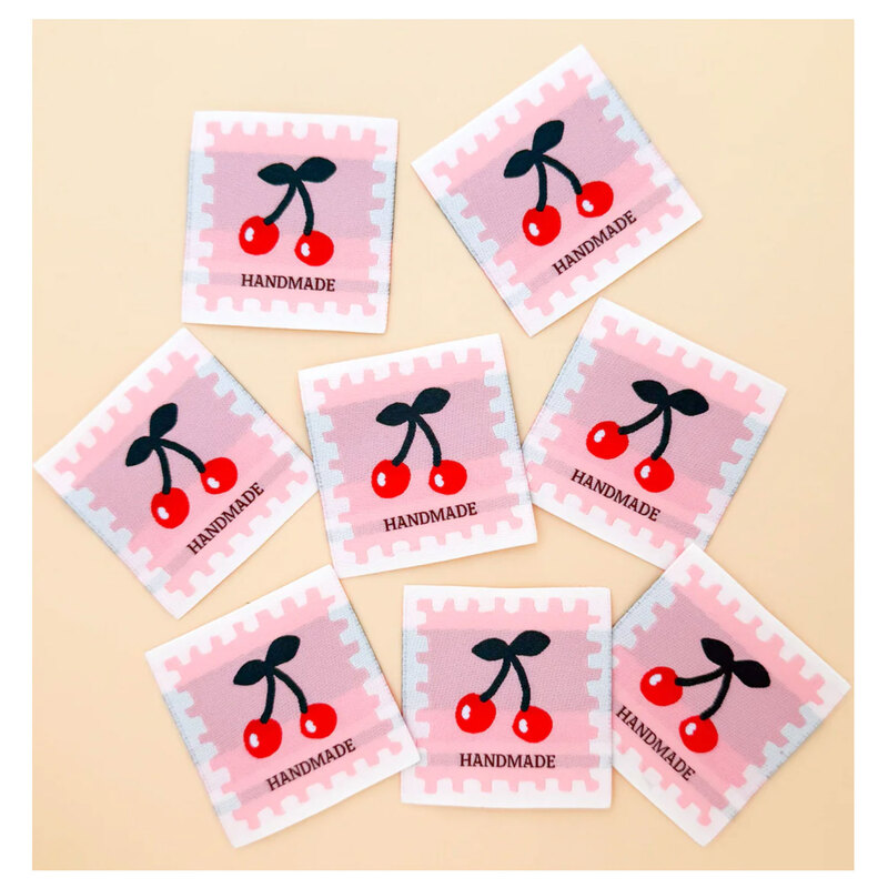 8 loose premium woven sew-in labels spread out on a cream background.