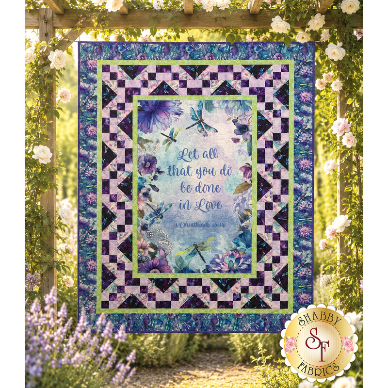 The completed Panel quilt staged on a white shiplap wall featuring inspirational quote hangs on a wall above a white rocking chair.