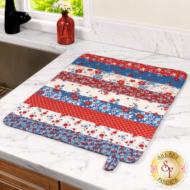 The finished Dry Ideas mat colored in red, white, and blue fabrics from the Front Porch Charm collection, staged on a white marble countertop with coordinating décor.