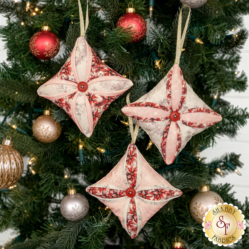 The three completed Cathedral Window Ornaments, colored in soft pink, cream, and red fabrics from the Christmas Magic collection, hung on a decorated Christmas Tree.