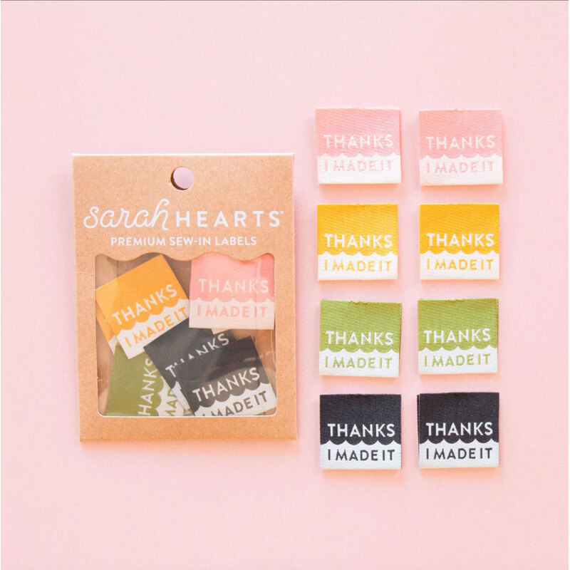 A package of the thanks i made it Labels next to 8 individual labels on a pink background to show scale and detail.