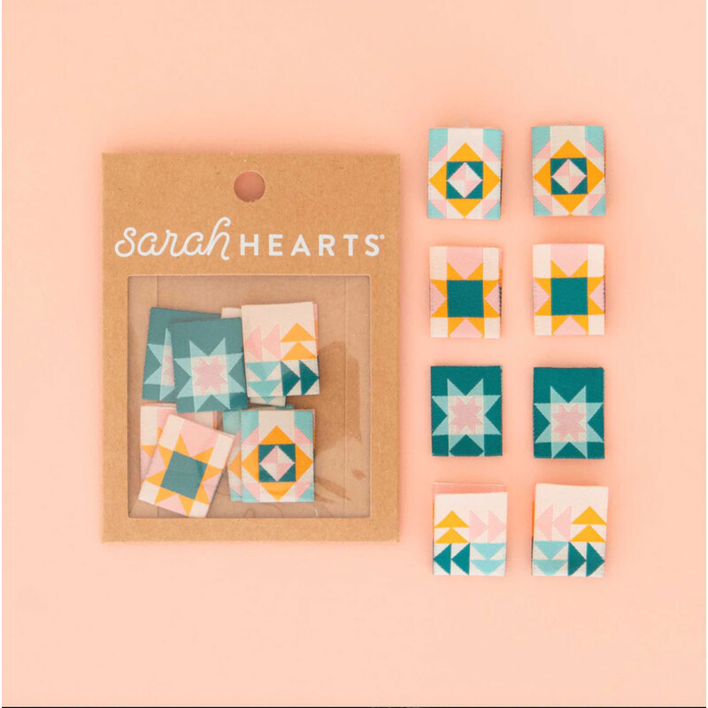 A package of quilt block Labels next to 8 individual labels on a pink background to show scale and detail.