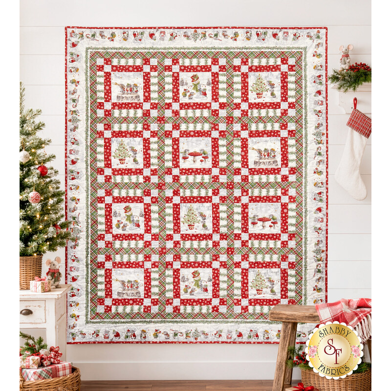 The completed Merry Mouse-mas Quilt, colored in gray, white, red, and green flannel fabrics from The Christmas Mouse collection by Northcott Fabrics, hung on a white shiplap wall and staged with coordinating decor.