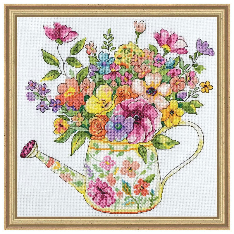 a framed and completed cross-stitch design depicting a floral watering can filled with vibrant floral blooms