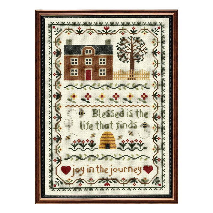 framed sampler style cross stitch project featuring a house, florals, a bee hive, and inspirational texts decorated with a double border.