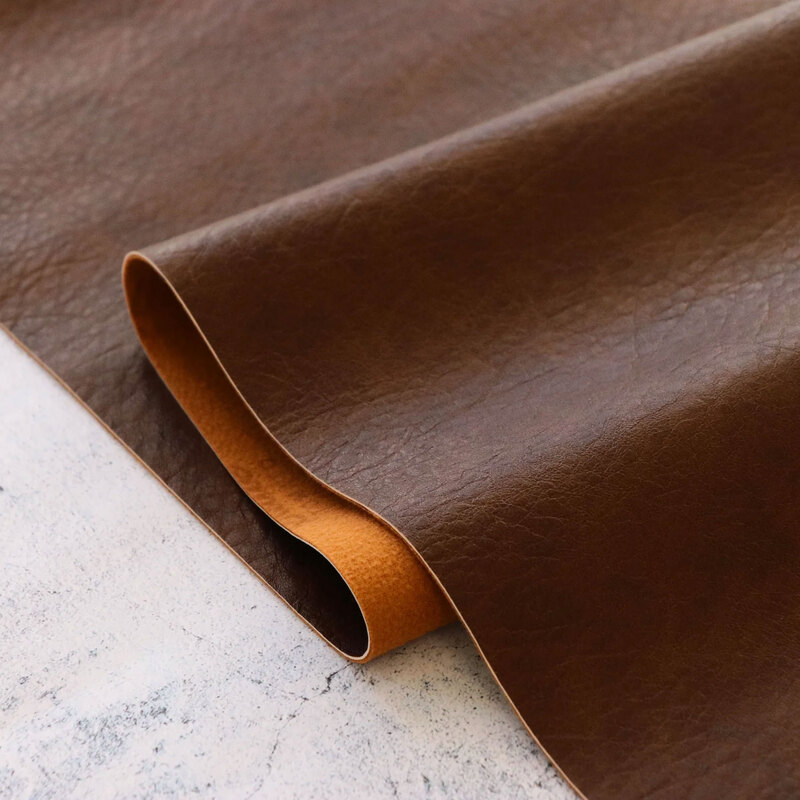 A shot of Brown Legacy Faux Leather, artfully draped over itself on a marble countertop.