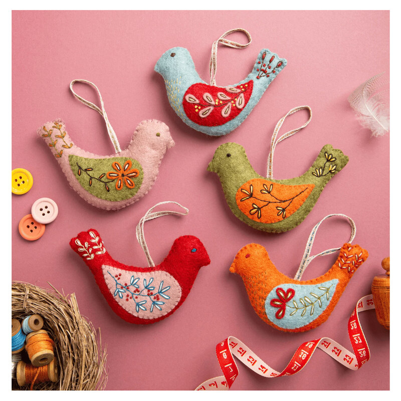 The completed folk bird ornaments on a table surrounded by sewing notions. 