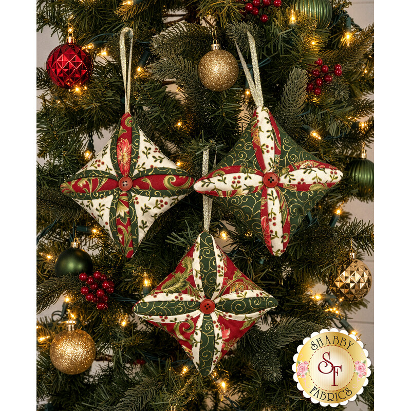 The three completed Cathedral Window Ornaments, colored in cream, green, and red fabrics from the Merry Manor Metallic 2025 collection, hung on a decorated Christmas Tree.