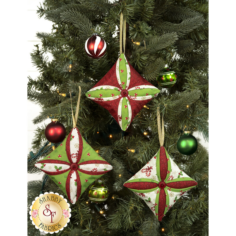 The three completed Cathedral Window Ornaments, colored in bright green, red, and cream fabrics from the Peppermint & Pine collection, hung on a decorated Christmas Tree.