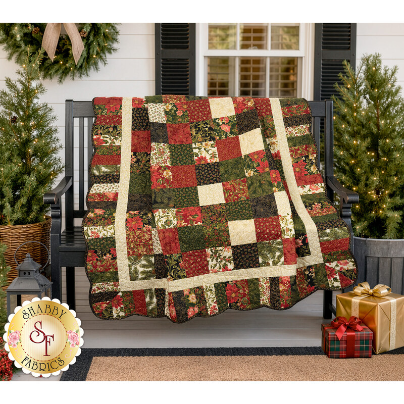 The completed Holiday Charm Quilt, colored in cream, green, and red fabrics from the Merry Manor Metallic 2025 collection, artfully draped over a black bench on a white porch, staged with coordinating plants and décor.