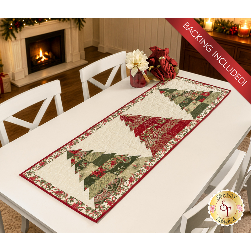 The completed Tree Farm Table Runner colored in cream, red, green, and black fabrics from the Candlelight Christmas collection by Moda Fabrics, staged on a white table with coordinating décor.