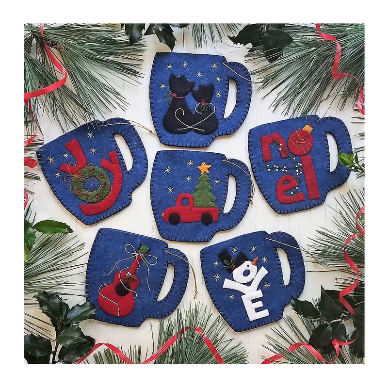 Photo of 6 mini mug ornaments on a white table top with pine tree boughs. Each stocking has a different motif including cats, love, a guitar, and a little red truck hauling a christmas tree. 