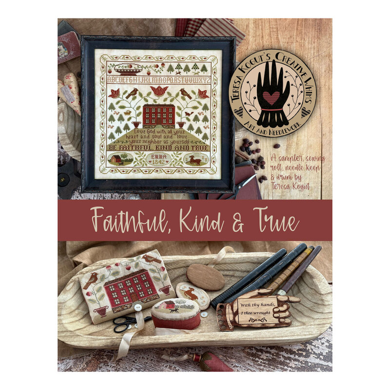 Finished Faithful, Kind & True cross stitch pattern in a black frame on top of an assortment of household items and a wooden bowl above the sewing roll, needle keep, and needle drum.