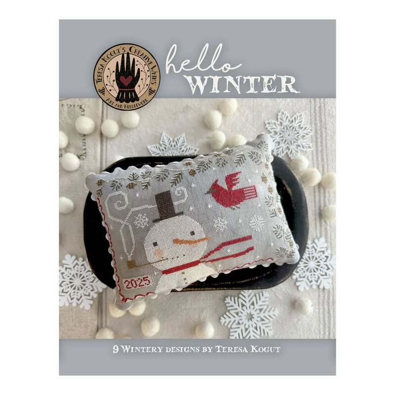 Finished Cardinal's Friend pattern on a pillow surrounded by cotton balls and snowflakes for the cover of Hello Winter.