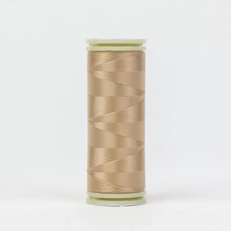 A spool of WonderFil DecoBob DB-217 Nude thread on a white background.