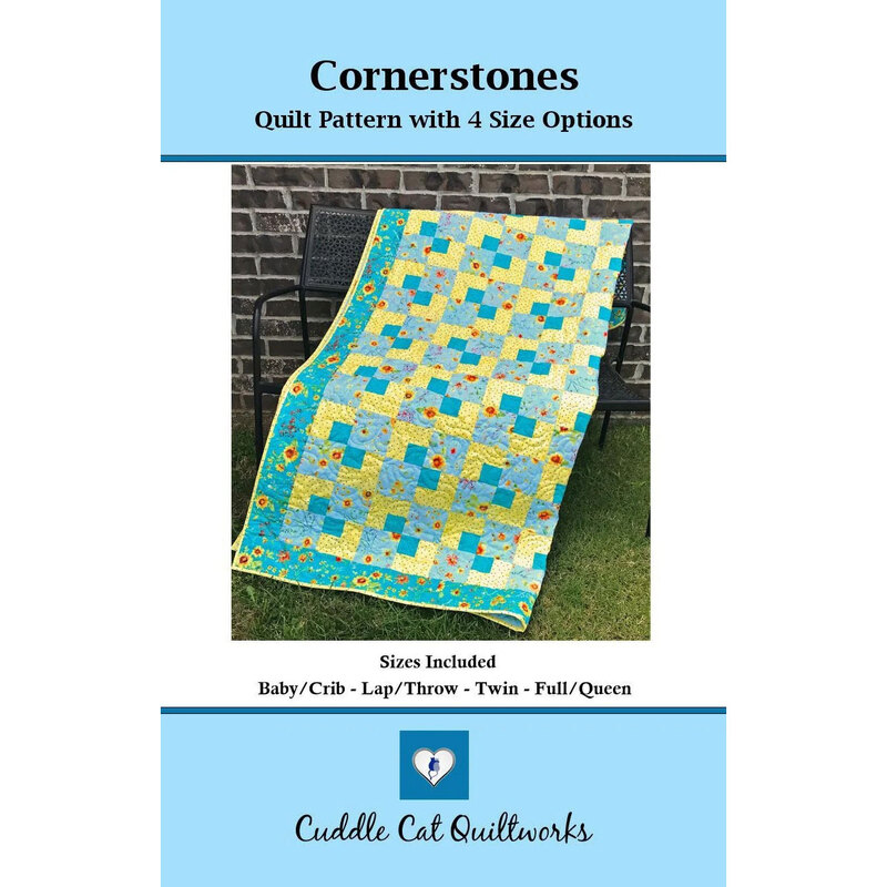 Cover of the finished Cornerstones quilt in a turquoise and yellow fabrics hung on a metal bench.