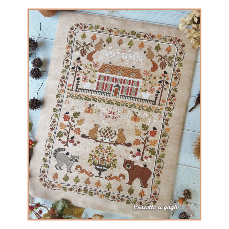 Finished Autumn Sampler cross stitch pattern with autumn colors, motifs, animals, acorns, and more on a linen fabric.